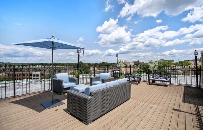 a rooftop patio with couches and an umbrella and a pool