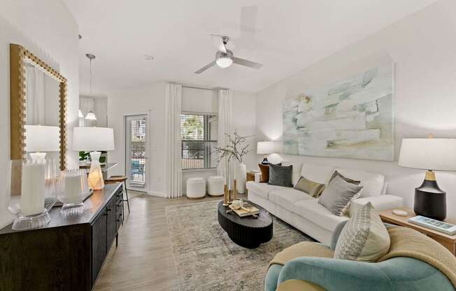A living room with a white couch, a coffee table, and a painting on the wall.