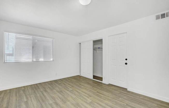 A room with a white door and a window with blinds.