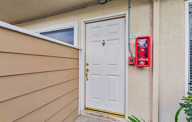 A red fire extinguisher is mounted on a wall next to a white door.