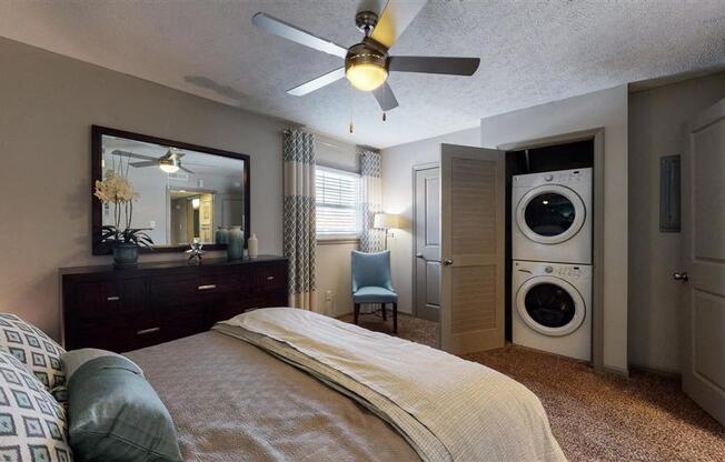 A bedroom with a bed, a dresser, a mirror, and a washing machine.
