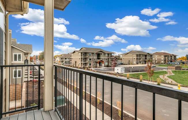 A balcony overlooks a street with houses and trees.