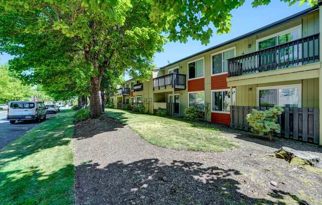 a street view of a row of townhomes with cars parked on the side of the