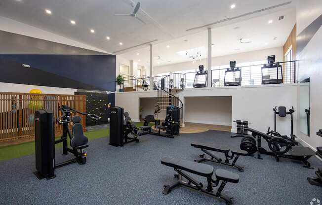 A gym with a variety of equipment including weights, a bench press, and a treadmill.