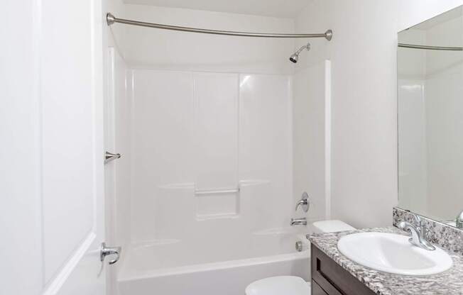 A white bathroom with a toilet, sink, and bathtub.