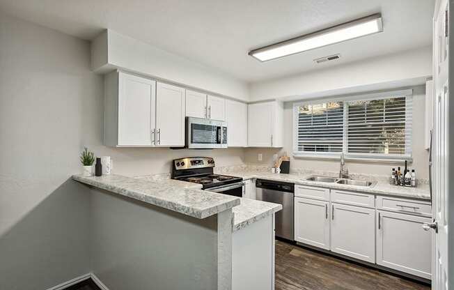 Model Kitchen with White Cabinets and Wood-Style Flooring at Broadmoor Village Apartments in Salt Lake City, UT.