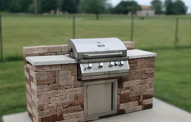 a small brick outdoor kitchen with a grill on it