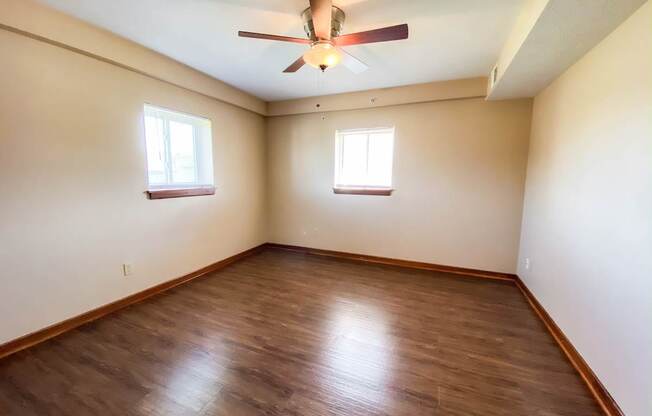 an empty bedroom with wooden floors and a ceiling fan