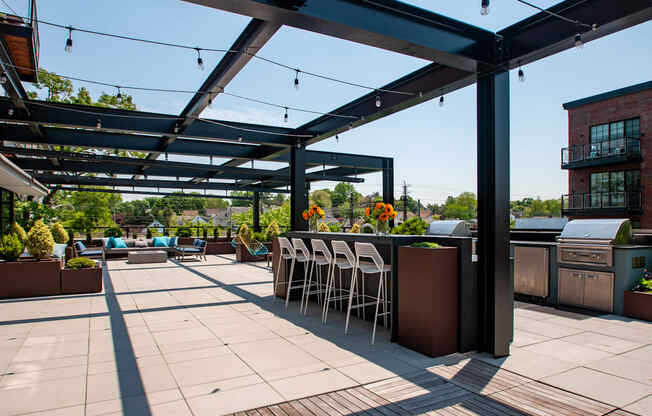 a patio with a bar and chairs under a roof