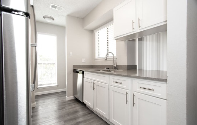 an empty kitchen with white cabinets and a stainless steel refrigerator