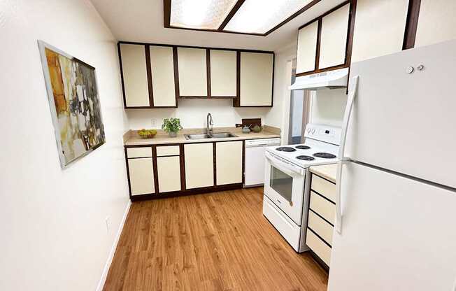 A kitchen with white appliances and wooden floors.