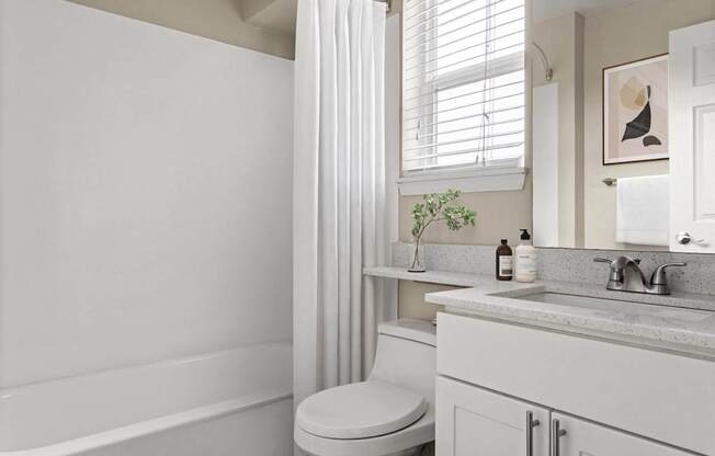 A white bathroom with a toilet, sink, and bathtub.