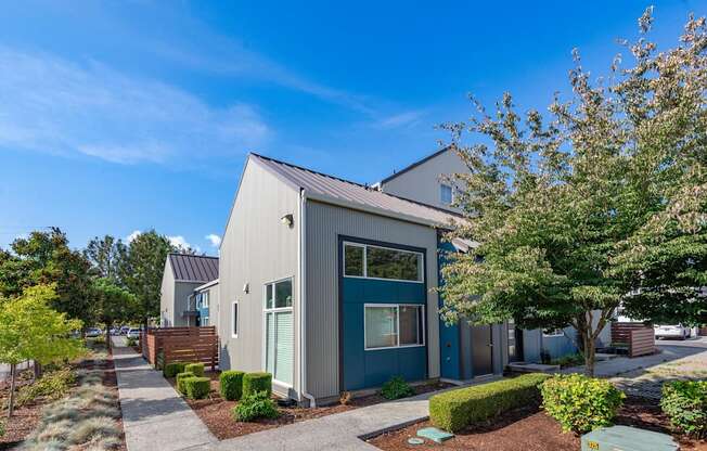 a gray and blue house with trees and a sidewalk