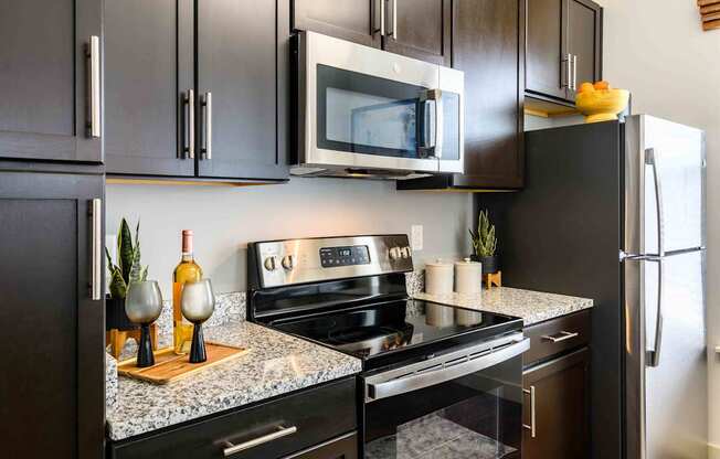 A modern kitchen with a black refrigerator, microwave, and stove.