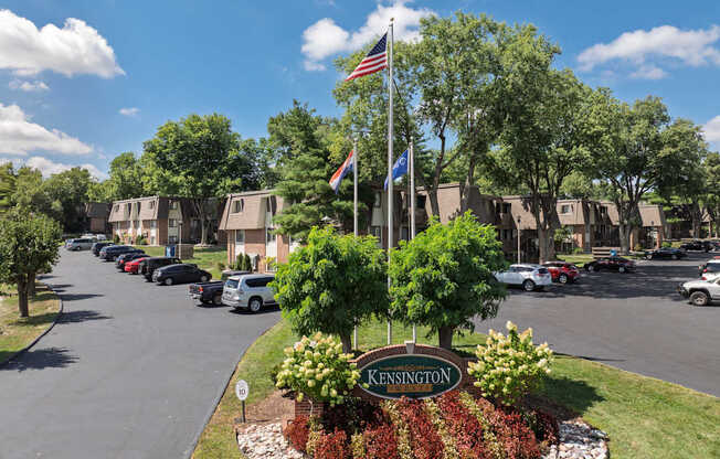 A street view of Kensington with cars parked on the side and trees lining the road.