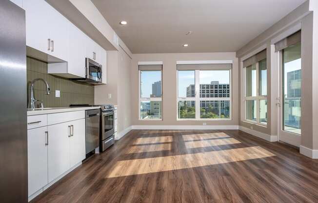 a kitchen and living room with hardwood floors and large windows