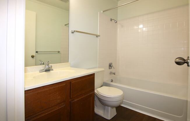 A white toilet sits next to a white bathtub in a bathroom.
