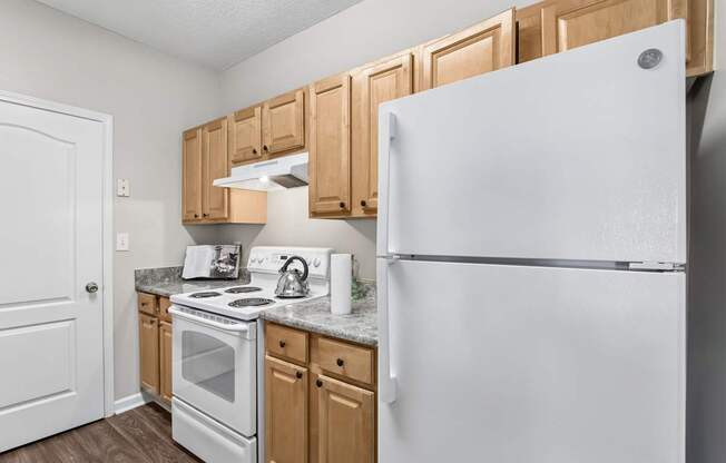 A white refrigerator stands in a kitchen with wooden cabinets.