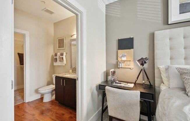 a bedroom with a desk and a bathroom with a toilet at Link Apartments® Brookstown, Winston Salem, NC, 27101