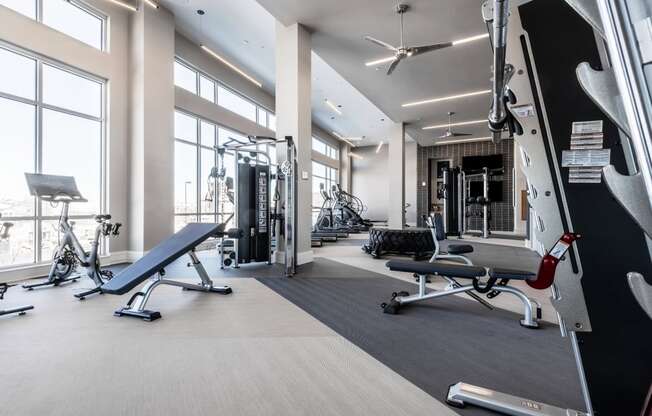 a spacious fitness center with floor to ceiling windows and a treadmill and other exercise equipment
