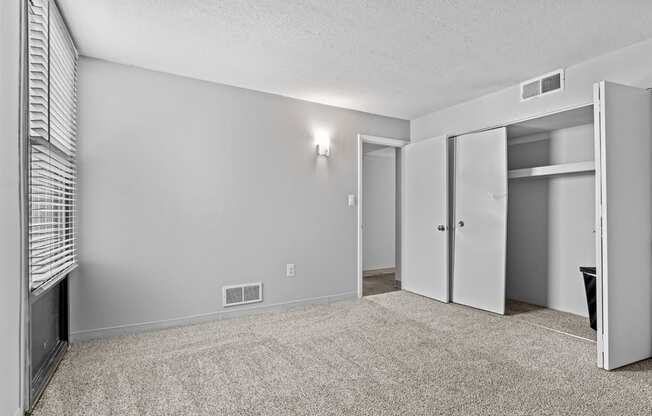 the living room is empty and has mirrored closet doors