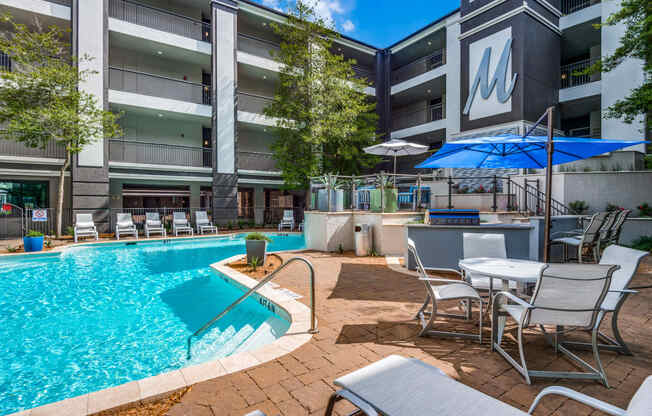 a swimming pool with tables and chairs next to a building