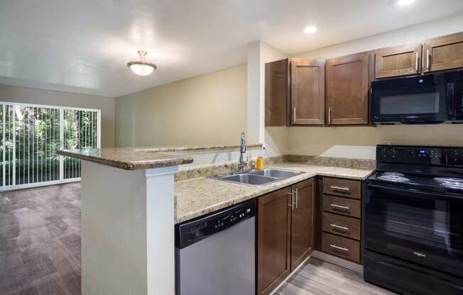 A kitchen with brown cabinets, black stove and stainless dishwasher at Arcadia Townhomes, Federal Way, WA