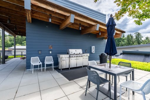 the patio has an outdoor grill and table with chairs and an umbrella