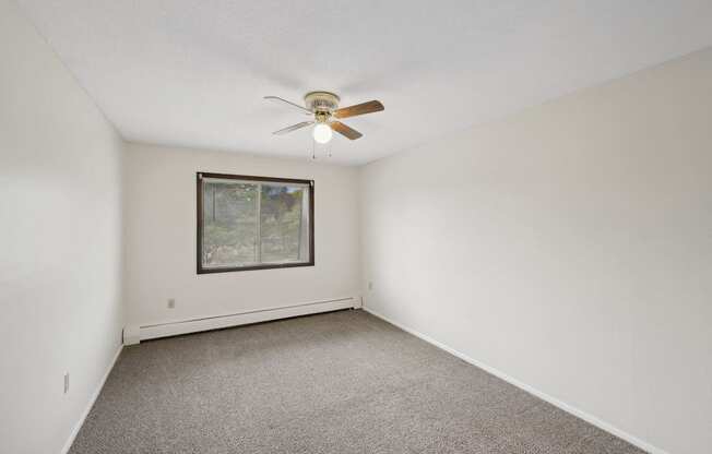 the living room of an empty home with white walls and a ceiling fan