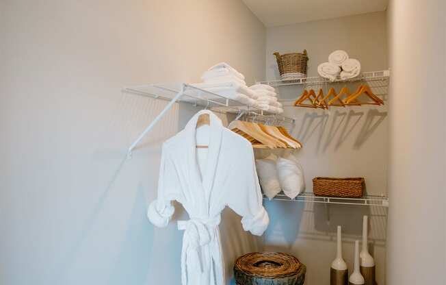 a walk in closet with a white robe and a basket