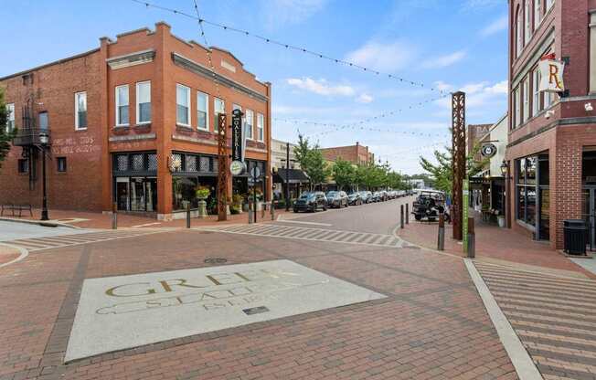 Downtown Greer, SC city square, with brick streets and a gold engraving on the ground which reads "Greer Station."