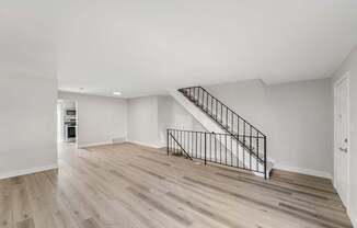 A spacious room with a staircase and wooden flooring.