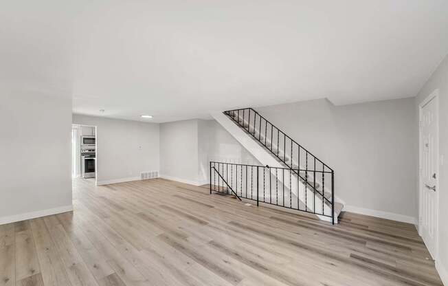 A spacious room with a staircase and wooden flooring.
