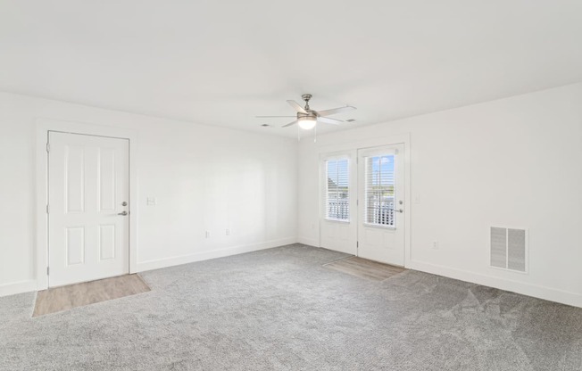 A spacious room with a ceiling fan and carpeted floor.
