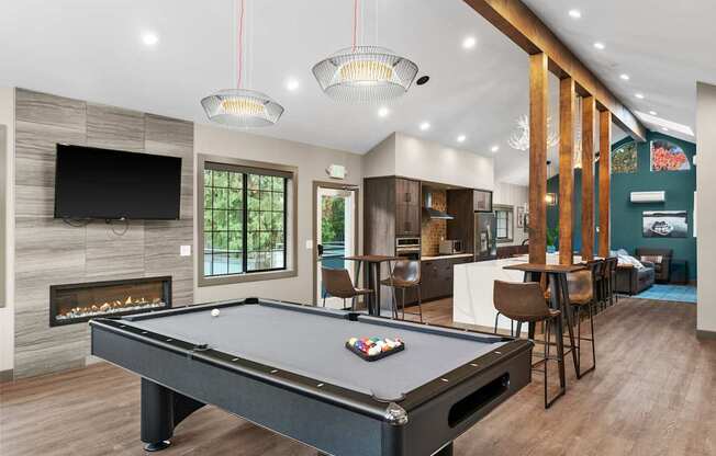 A pool table is in the middle of a room with a fireplace and a television.