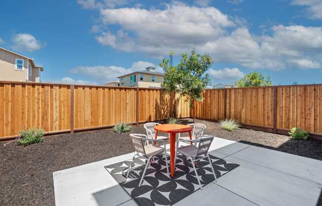 a patio with a table and chairs in front of a wooden fence