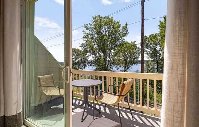 a balcony with a table and two chairs and a view of the water