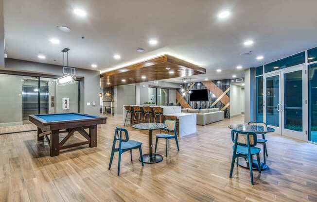 A room with a pool table and chairs.