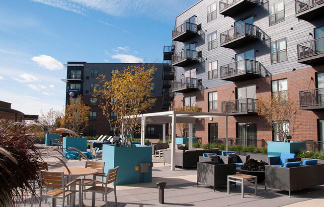 Outdoor community kitchen and lounge area, with tables and couches, balconies in background
