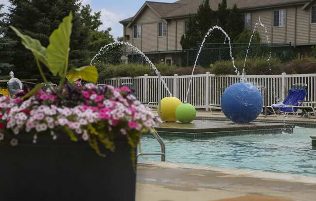 a swimming pool with water sprinklers and a house in the background at Village Club of Rochester Hills, Michigan, 48317