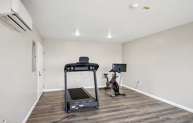 A treadmill is in the middle of a room with a wooden floor.