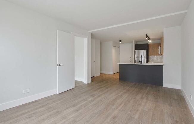 a renovated living room and kitchen with white walls and wood floors