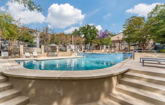 a swimming pool with stairs next to it and trees