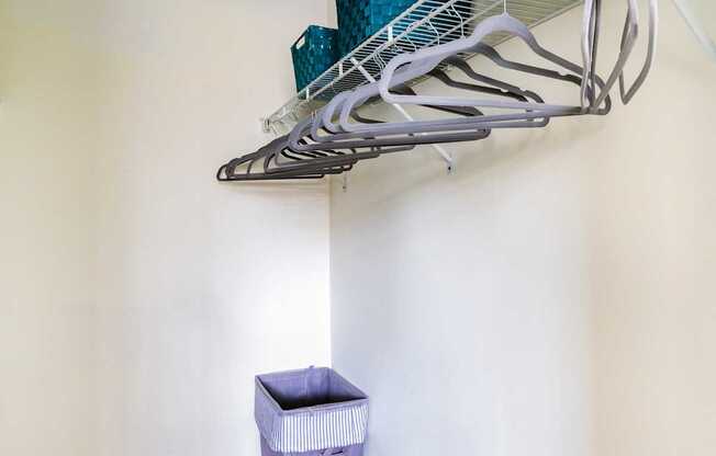 A white wall with a shelf and a blue container on it.