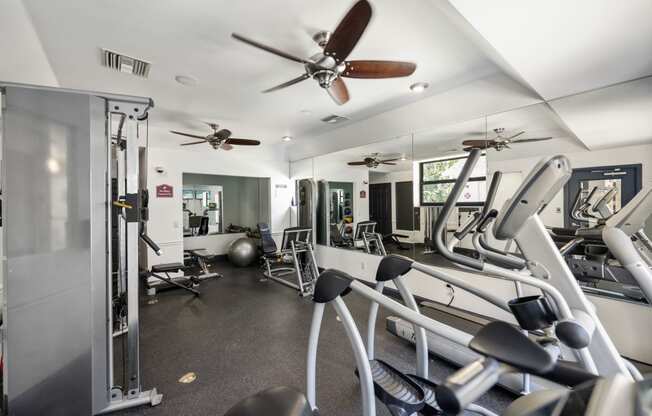 a gym with cardio equipment and a ceiling fan