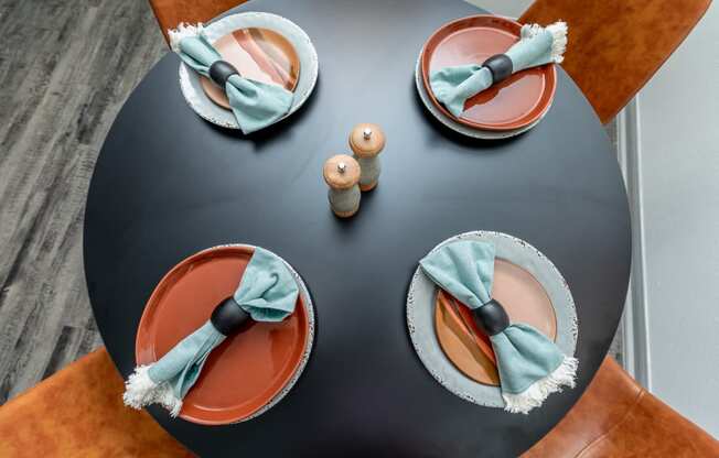 a table with two plates and two napkins on it with blue and orange plates