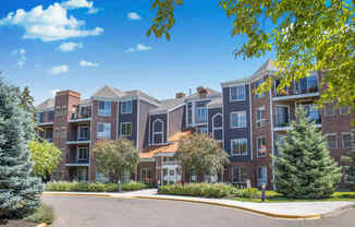 an exterior view of an apartment building with trees and a driveway