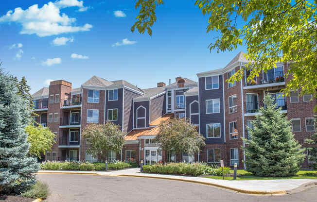 an exterior view of an apartment building with trees and a driveway