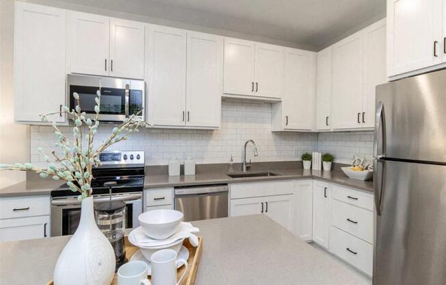A kitchen with white cabinets and a tray with a vase and dishes on it.