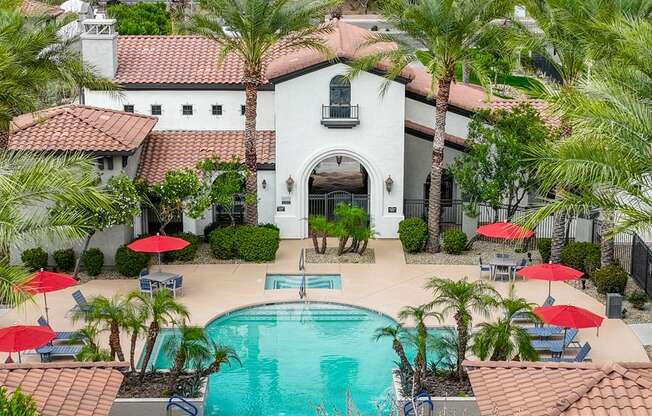 a swimming pool in front of a house with palm trees